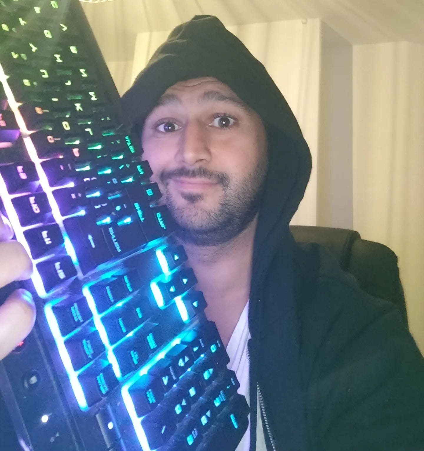 Dan Conn wearing a hoody and holding a rainbow illuminated black keyboard